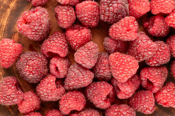 Sweet ripe raspberries on a clay plate, macro, top view.
