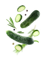 Fresh cucumbers, rosemary and peppercorns falling against white background