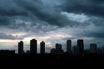 Fototapeta premium Dramatic stormy sky over a silhouetted cityscape at dusk with towering buildings