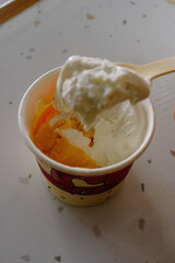 A creamy scoop of gelato is being eaten with a red spoon from a bright red cup, a vibrant and delicious summer dessert