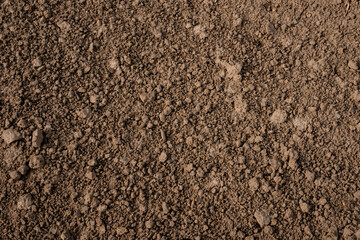 Close-up texture of freshly tilled brown soil with natural clumps and granules, ideal for...