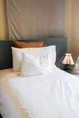 Hotel room scene with bed pillows and lamp on table,White soft pillows on bed,contemporary,Space for text.