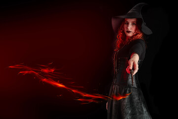 Witch with a magic wand casts a spell. Young woman, magician girl with red hair, dressed in...