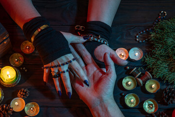 Witch palmistry fortune-telling reading man's palm, witchcrafting, performing ritual among candles,...