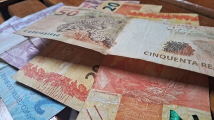 Brazilian real notes superimposed on a wooden background