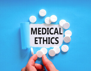 Medical ethics symbol. Concept words Medical ethics on beautiful white paper. White pills tablets. Doctor's hand. Beautiful blue background. Medical healthy lifestyle medical ethics concept.
