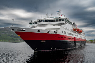 Obraz premium Big Cruise Ship And Ferry Arrives In The Harbor Of Stokmarknes At The Lofoten In Norway