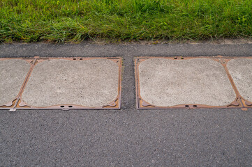 Concrete slabs filling drainage ditch next to asphalt road and grass