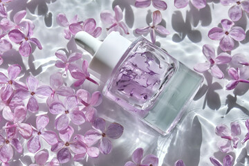 A bottle of hyaluronic serum in lilac flowers in the water.