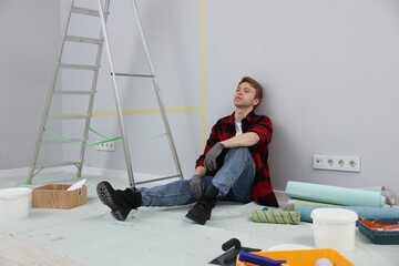 Tired man having break during renovation in room