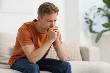 Sad thoughtful man on sofa at home