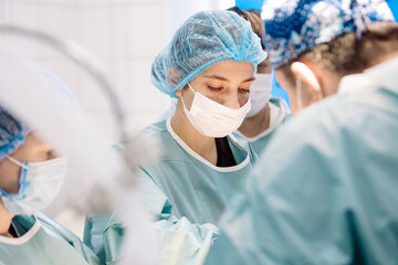 Surgical team in operating room, focused on procedure, wearing masks and scrubs, demonstrating...