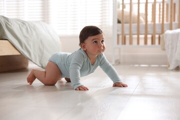 Cute little baby crawling on floor at home, space for text