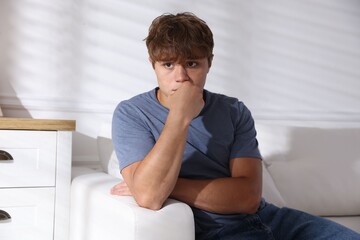 Teenage boy suffering from panic on sofa at home