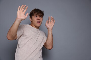 Teenage boy suffering from panic attack on grey background. Space for text