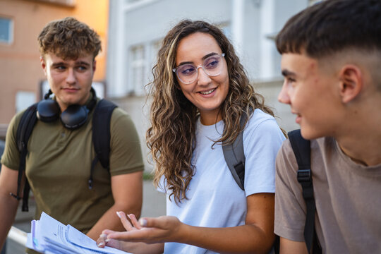 Smiling students discussing notes outdoors after school