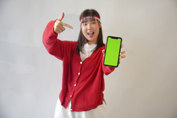 Cheerful Indonesian woman wearing a red sweater and white T-shirt shows a photocopying space on her...