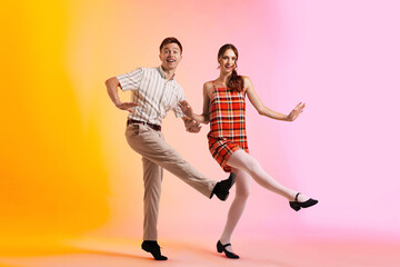 Happy couple in retro outfits dancing on color background