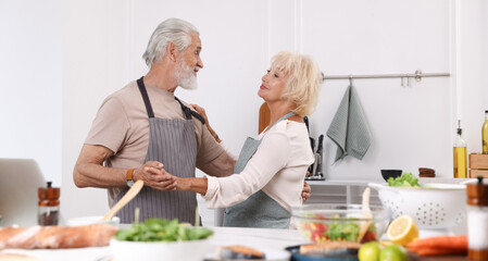Elderly couple dancing after cooking together in kitchen