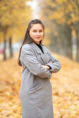 Portrait of a young beautiful dark-haired girl in an autumn park.