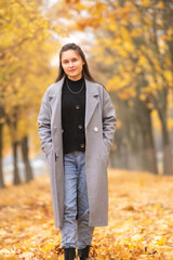 Portrait of a young beautiful dark-haired girl in an autumn park.