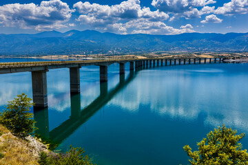 Aerial view of Lake Polyfytos in Greece with a curved bridge,