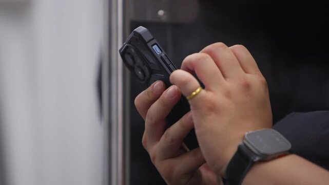 Slow motion of man holding metal metro pole with one hand and smartphone in the other inside Taipei metro during commute