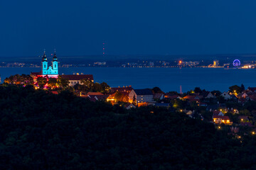 Illuminated church and village at night by the lake, panoramic view of Lake Balaton from the Tihany lookout in Hungary.