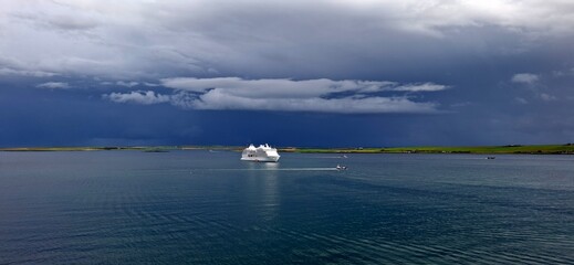 kirkwall united kingdom aug 9 202 Cruise Ship Sailing Under Stormy Sky Near Scenic Green Coastline
