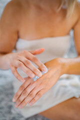 Fototapeta premium Woman applying moisturizing cream on her hands after shower