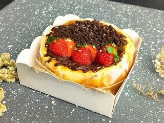burnt cheesecake, with chocolate topping and strawberries
