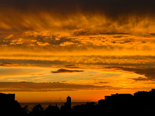 Golden sunset sky over dark town 