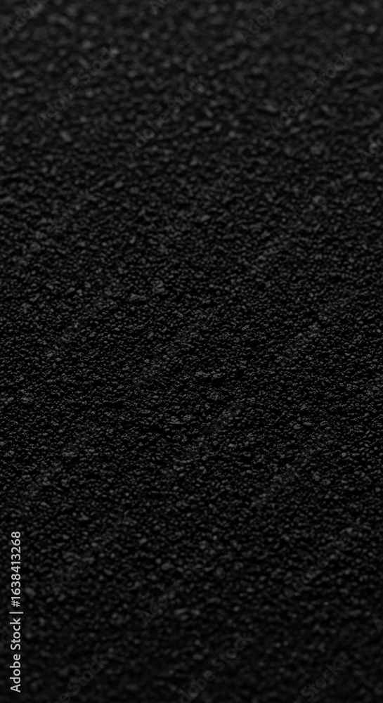 Poster close-up of black granular texture, showing depth and subtle variations in tone, ideal as a backgrou