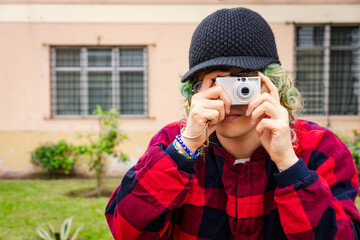 Creative young photographer aiming vintage compact camera in urban environment.