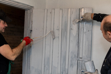 A group of men engaged in painting a wooden wall as part of their home renovation project