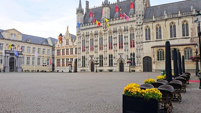 Bruges City Hall in the early morning. Walking motion with cafe tables and beautiful flowers, Belgium