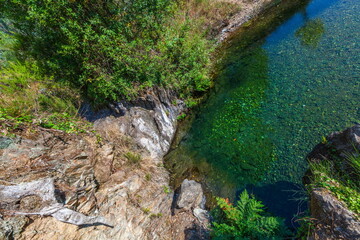 A serene natural pool with crystal-clear water reflects the surrounding greenery