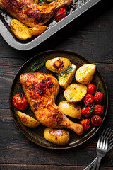 Oven roasted chicken leg quarter with potatoes, tomatoes
