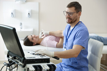 Sonographer conducting ultrasound examination of woman's thyroid gland in clinic