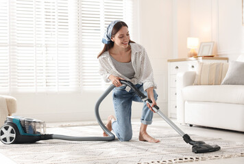 Woman cleaning carpet with vacuum cleaner at home