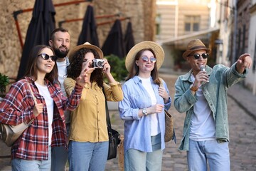 Guide with microphone and group of tourists on city street during excursion