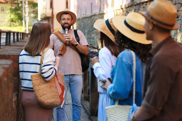 Guide with microphone and group of tourists on city street during excursion