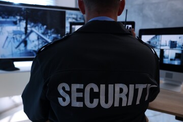 Security guard monitoring CCTV cameras in office, back view