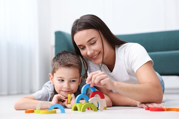 Mother and her son playing with toys on warm floor at home. Heating system