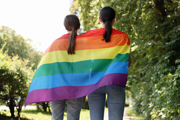 LGBT concept. Women with rainbow flag outdoors, back view