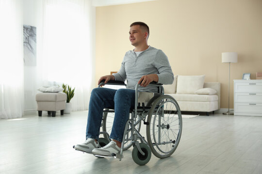 Young man in modern wheelchair at home - Powered by Adobe