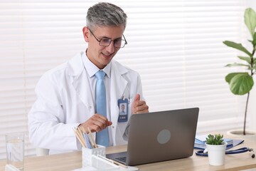 Fototapeta premium Telemedicine. Doctor having video call with patient via laptop indoors