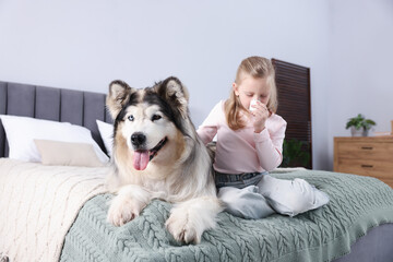 Girl suffering from allergy with her dog on bed at home