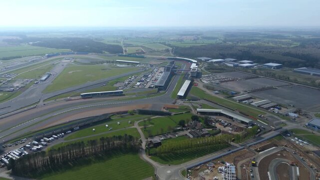 Aerial view of the Silverstone Circuit, where the asphalt ribbon winds through the green landscape, a symphony of speed and nature, Silverstone, United Kingdom.