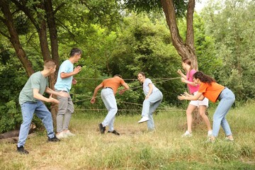 Team building. Group of happy people playing spider web game outdoors
